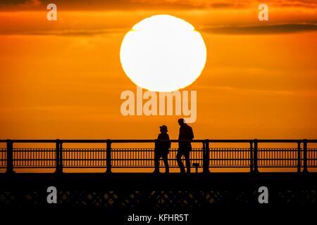 Southport, Merseyside, Sonnenuntergang über Southport Pier. 29. Oktober 2017. UK Wetter. Als halbe Amtszeit nähert sich dem Ende, Familien machen Sie einen Spaziergang entlang der Promenade als atemberaubende Sonnenuntergang schmiegt sich in den Horizont über den berühmten Pier in Southport, Merseyside. Erst im Jahre 1860 eröffnet, es erstreckt sich über eine Länge von 1.108 Meter (3.635 ft) und der Zweitlängste in Großbritannien. Es war grad II am 18. August 1975 aufgeführt. Die Straßenbahn fuhr von der Promenade zum Pier Head zu verschiedenen Zeiten in der Geschichte der Pier, vor kurzem von August 2005 bis Juni 2015. Credit: cernan Elias/Alamy leben Nachrichten Stockfoto