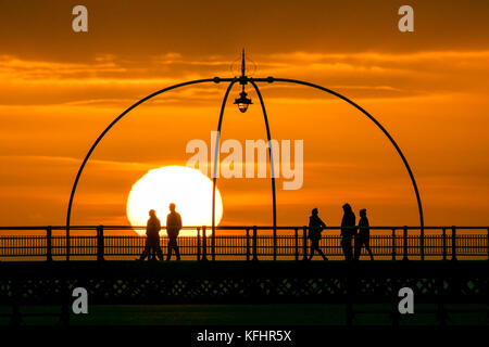 Southport, Merseyside, Sonnenuntergang über Southport Pier. 29. Oktober 2017. UK Wetter. Als halbe Amtszeit nähert sich dem Ende, Familien machen Sie einen Spaziergang entlang der Promenade als atemberaubende Sonnenuntergang schmiegt sich in den Horizont über den berühmten Pier in Southport, Merseyside. Erst im Jahre 1860 eröffnet, es erstreckt sich über eine Länge von 1.108 Meter (3.635 ft) und der Zweitlängste in Großbritannien. Es war grad II am 18. August 1975 aufgeführt. Die Straßenbahn fuhr von der Promenade zum Pier Head zu verschiedenen Zeiten in der Geschichte der Pier, vor kurzem von August 2005 bis Juni 2015. Credit: cernan Elias/Alamy leben Nachrichten Stockfoto