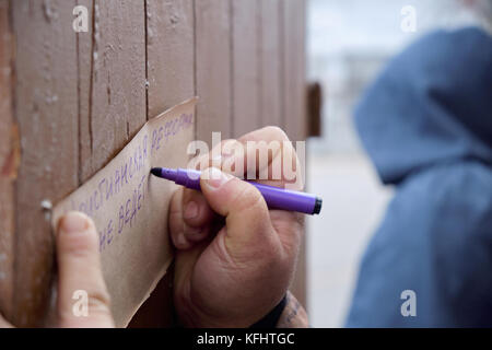 Kryvyi Rih, Ukraine. Oktober 2017. Hand mit Filzstift schreibt Thesen auf braunem Papier mit verschwommenem Mann in der Kapuze, der Martin Luther während der Veranstaltung zum 500. Jahrestag der Reformation widmet. Credit: Dmytro Aliokhin/Alamy Live News Stockfoto