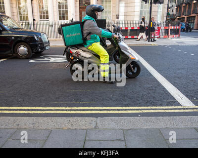 Eine Deliveroo rider liefert einige Essen zum Mitnehmen auf einem Moped Stockfoto