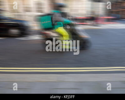 Eine Deliveroo rider liefert einige Essen zum Mitnehmen auf einem Moped Stockfoto