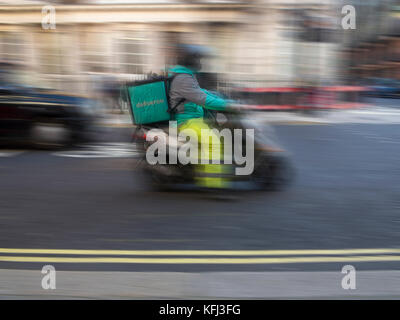 Eine Deliveroo rider liefert einige Essen zum Mitnehmen auf einem Moped Stockfoto