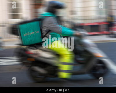 Eine Deliveroo rider liefert einige Essen zum Mitnehmen auf einem Moped Stockfoto