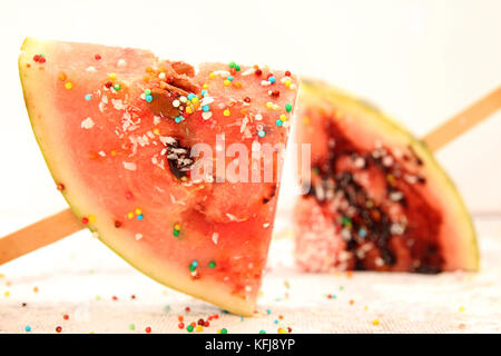 Scheiben Wassermelone in Eis Form. Beliebte Sommer Obst Wassermelone mit Puderzucker und Schokolade auf Stick. Wassermelone in popsicle Form. Stockfoto