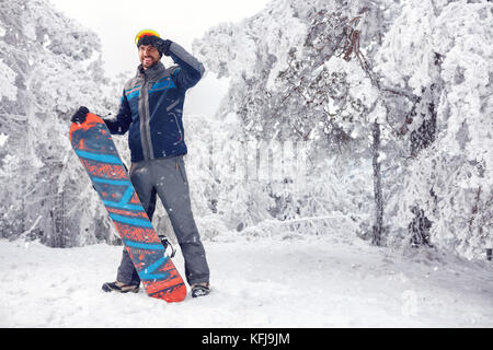 Jungen gutaussehenden männlichen Snowboarder auf dem Berg Stockfoto