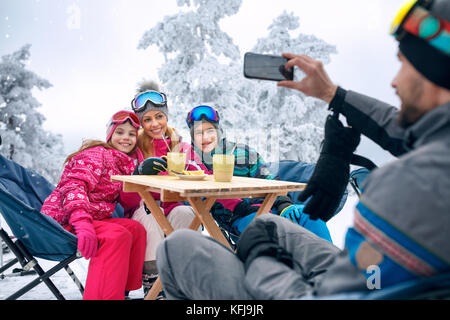 Glückliche Familie dauert Kaffee Pause beim Skifahren auf dem Berg Stockfoto