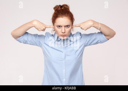 Ich will nicht von Ihnen zu hören! Aggressive Ingwer Frau mit Fingern auf den Ohren und Kamera. studio Shot Stockfoto