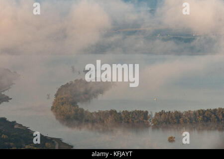 Nebel erhebt sich über presa Isabel Allende See bei Sonnenaufgang als lange Fischerboot schwimmt auf dem Wasser außerhalb der Kolonialstadt San Miguel de Allende, Mexiko. Stockfoto