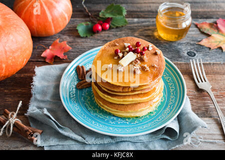 Kürbis Pfannkuchen mit Pekannuss, Butter, Beeren und Honig auf einem blauen Schild. Saisonale Herbst essen Stockfoto