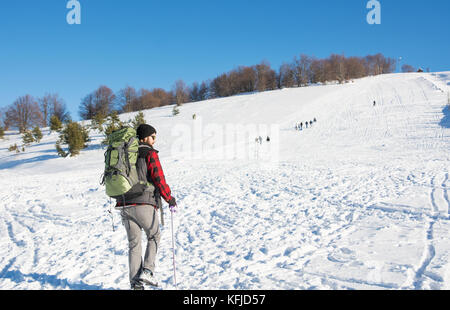 Männliche Wanderer mit Rucksack auf schneebedeckten Berg Stockfoto