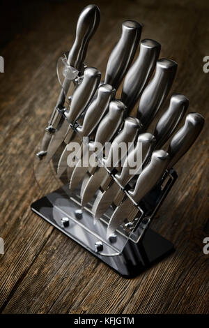 Moderne Küchenmesser aus Stahl in einem Messerblock auf rustikalem Holzhintergrund Stockfoto