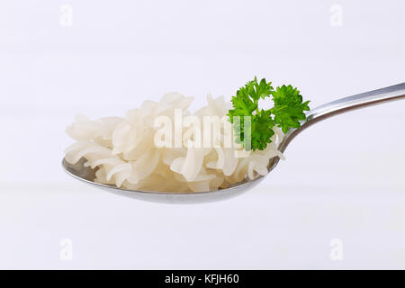 Löffel, gekochten Reis Pasta Fusilli auf weißem Holz- Hintergrund Stockfoto