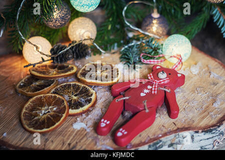 Rot Holz- Bär auf einer Disc Birkenholz vor Weihnachten ein Zweig mit beleuchteten Weihnachtskugeln eingerichtet Stockfoto