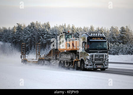 Paimio, Finnland - Januar 17, 2016: maßgeschneiderte Volvo FH 16 750 mit Gemälden und Bull Bar von Moto-olli Oy hols Liebherr R918 Kettenbagger auf Mo Stockfoto