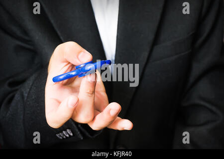 Finger der Männer halten die Spinner aus der Nähe. Ein Kerl in einem Anzug und ein weißes Hemd. Geschäftsmann entlastet von Stress am Arbeitsplatz. Leistungsstarke Spinner, tw Stockfoto