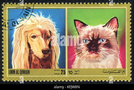 Eine Briefmarke in Umm al Qiwain zeigt Katze und Hund aus Serien: Verschiedene Rassen von Hunden und Katzen, um 1971 Stockfoto