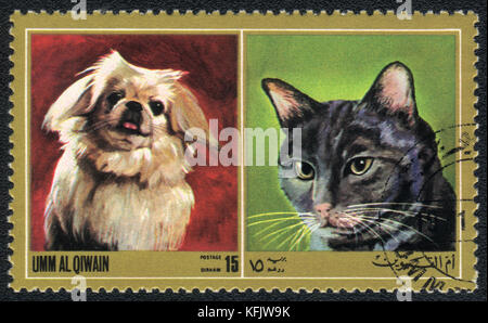 Eine Briefmarke in Umm al qiwain gedruckt zeigt Katze und Hund ab Serie: unterschiedliche Rassen von Hunden und Katzen, ca. 1971 Stockfoto