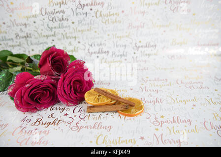 Weihnachten essen Fotografie Bild mit Weihnachten Glitter rote Rosen und Zimtstangen auf Weiß glänzenden Geschenkpapier Hintergrund mit festlichen schreiben Stockfoto