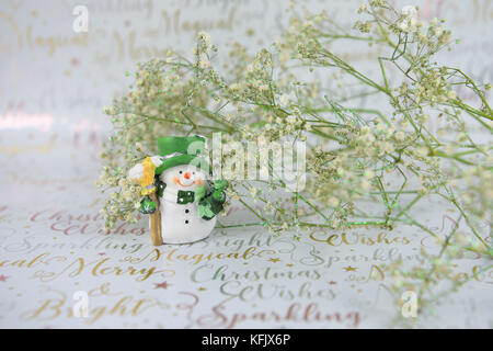 Weihnachten fotografie Bild mit grün weiß xmas glitter Blumen und niedliche Happy snowman Dekoration auf festliche Gold schreiben Geschenkpapier Stockfoto