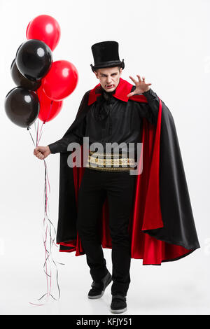In voller Länge Porträt der stattlichen kaukasischen Vampir in Schwarz und Rot halloween kostüm. Stockfoto