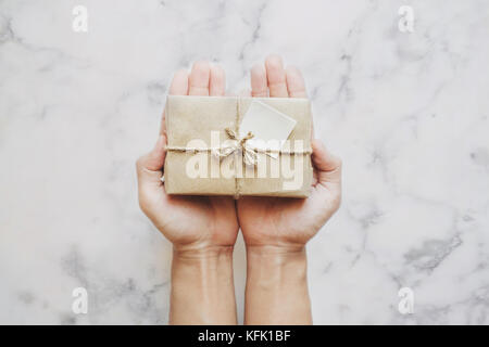 Hand Paket Geschenkbox, auf weißem Marmor Stein Tabelle Hintergrund Stockfoto