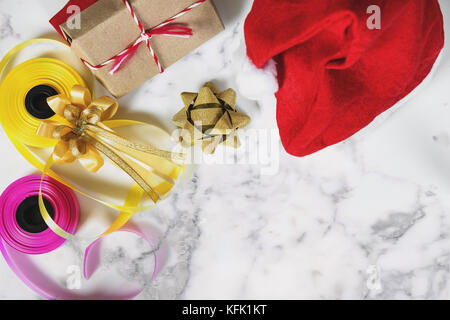 Weihnachten Geschenke Vorbereitung auf weißem Marmortisch mit kopieren. rote Weihnachtsmütze mit Geschenkbox und bunten Farbband Stockfoto