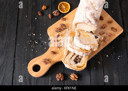 Hohe Betrachtungswinkel und einer köstlichen Pound Cake, geschnitten auf einem Grabenbagger, mit Mohn und Nüssen gefüllt, mit gerösteten Walnüssen und Mandeln umgeben, auf einem hölzernen ta Stockfoto