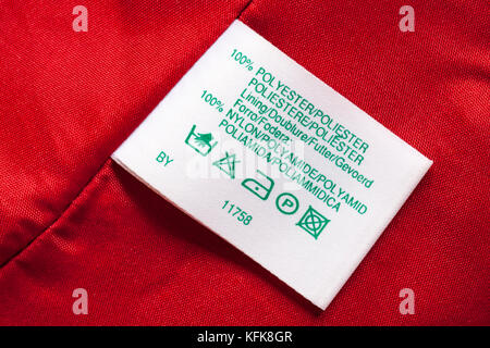 100% Polyester Innenfutter 100% Nylon Aufkleber in Rot Frau Kleidung mit Waschen pflege Symbole Anweisungen in verschiedenen Sprachen Stockfoto