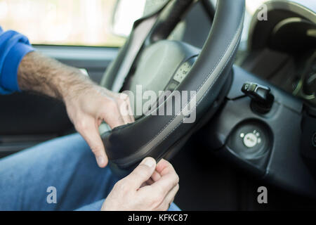 Der Mechaniker setzt weel Abdeckung am Lenkrad des Autos. Auto, in das Innere des Autos. die Abdeckung des Lenkrads. Stockfoto