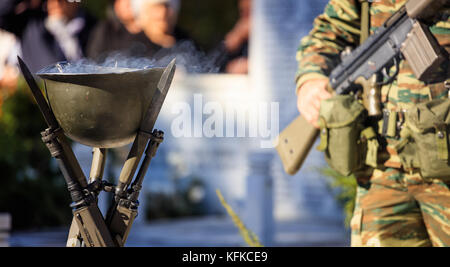 Brand in ein Soldat mit Helm und ein Soldat hält eine Waffe während einer Trauerfeier Stockfoto