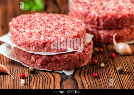 Rohes Rindfleisch Burger Steak, Schnitzel, chemische Pfeffer und Knoblauch auf ländlichen Holz- Hintergrund Stockfoto