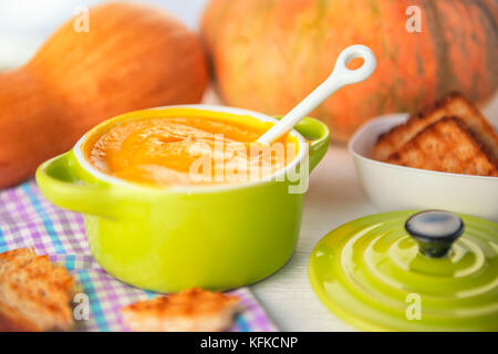 Hausgemachte cremige Kürbissuppe und Brot in der grünen Schale auf der Serviette, Konzept der Danksagung Stockfoto