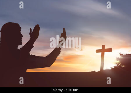 Silhouette Mann anheben Hand betend auf Sonnenuntergang Hintergrund zu Jesus Stockfoto