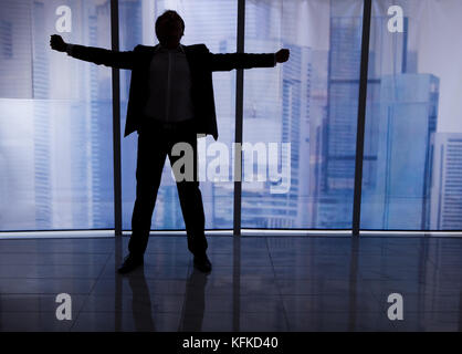 Volle Länge Rückansicht des Geschäftsmannes stehende Fenster ausgestreckten Arme von Office Stockfoto