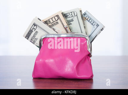 Vielzahl von Dollarnoten in rosa Handtasche auf Tisch Stockfoto