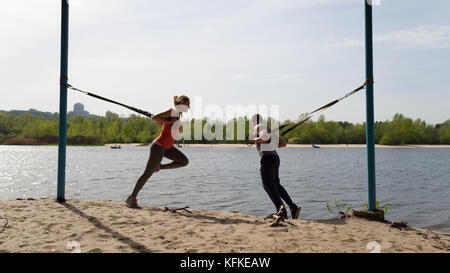 Mann und Frau tun Ausfallschritt Übungen mit trx Gang. Stockfoto