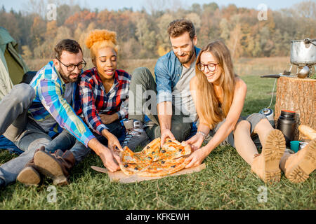 Freunde essen Pizza auf dem Campingplatz Stockfoto