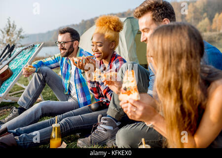 Freunde essen Pizza auf dem Campingplatz Stockfoto