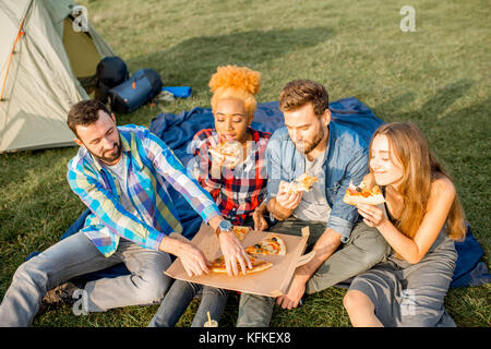 Freunde essen Pizza auf dem Campingplatz Stockfoto