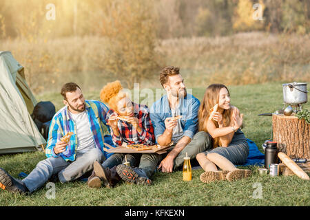 Freunde essen Pizza auf dem Campingplatz Stockfoto