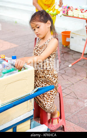 Ein wenig Thai Girl Hilft ihren Eltern, Wasser und Erfrischungsgetränke an einem Tempel in Bangkok, Thailand. Stockfoto