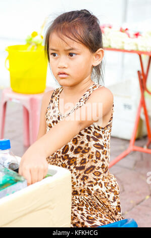 Ein wenig Thai Girl Hilft ihren Eltern, Wasser und Erfrischungsgetränke an einem Tempel in Bangkok, Thailand. Stockfoto