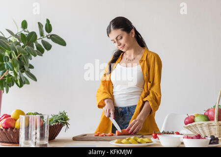 Lächelnde Frau schneiden Möhre Stockfoto