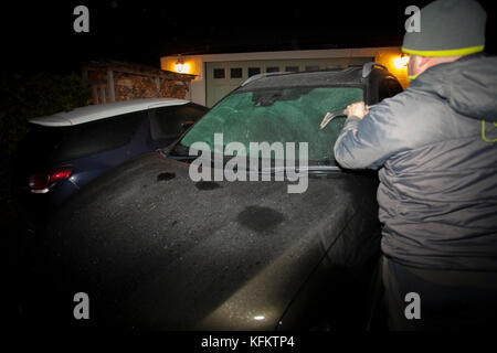 Flintshire, North Wales, UK. .De Wetter. Mit clearing Skies über Nacht viele heute Morgen wird das Aufwachen zu einem kalten frostigen Start aufgrund eines Arctic blast aus dem Norden werden. Ein Mann mit seinem Auto kratzen und Entfrostung der Frontscheibe nach einer Nacht starker Frost Stockfoto