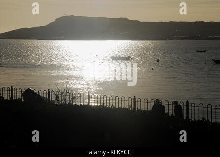 Weymouth, Großbritannien. 30 Okt, 2017. de Wetter. einen sonnigen, aber kalten Start in den Tag in Weymouth und Menschen gehen im nächsten Hafen nach Portland, mit der Isle of Portland in der Ferne Credit: stuart Hartmut Ost/alamy leben Nachrichten Stockfoto