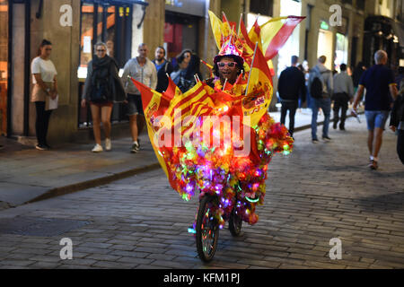 Der Lichtkünstler Jamal fährt auf seinem bunt verzierten Fahrrad mit spanischen Fahnen durch Barcelona, 29. Oktober 2017. Jamal, jamaikanischer Herkunft, befestigte mehrere Papierblumen, Lichterketten und spanische Fahnen an seinem Fahrrad und fährt nachts durch die Straßen. "Dies ist meine persönliche Demonstration für die Einheit Spaniens", sagt Jamal. Foto: Andrej Sokolow/dpa Stockfoto