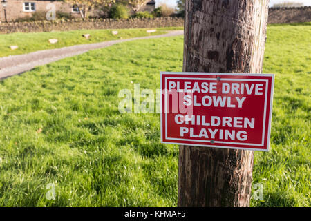 Auf einem Dorfplatz, Bitte fahren Sie langsam. Kinder spielen. Stockfoto