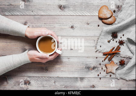 Frau mit der Tasse trinken. Holztisch mit weihnachtsplätzchen eingerichtet Stockfoto