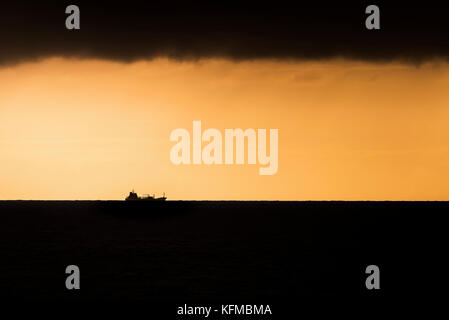 Sonnenuntergang - die Silhouette eines Schiffes gegen den feurigen Sonnenuntergang. Stockfoto