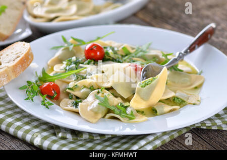 Nudeln gefüllt mit Spinat und Quark (Südtiroler Spezialität so genannte chlutzkrapfen') mit Ruccola butter Soße und Cocktail Tomaten serviert. Stockfoto